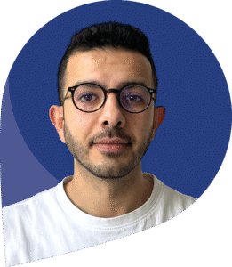 Mitarbeiter Ahmad Assad, vor blauem Hintergrund, schaut in die Kamera